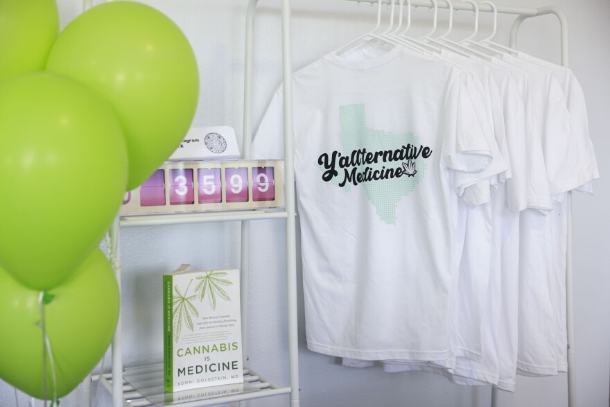 A display at a store consists of green balloons, a book called "Cannabis Is Medicine" and white T-shirts that say "Y'allternative Medicine."