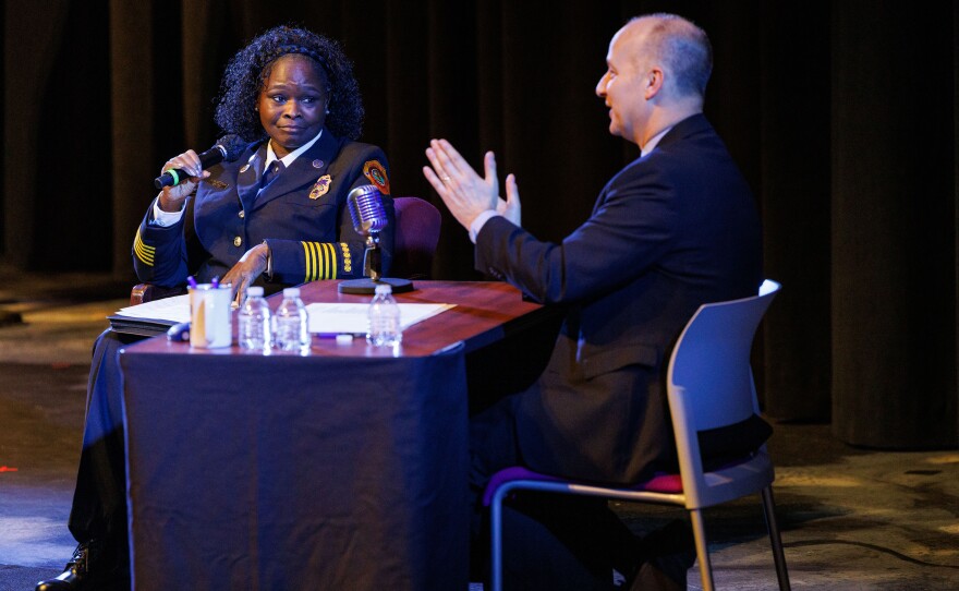 Lansing Fire Chief Carrie Edwards-Clemons, left, speaks during Lansing Mayor Andy Schor's State of the City Address at Dart Auditorium in Lansing, Mich., on March 18, 2026. Rather than giving a traditional speech, Schor, right, sat behind a talk show style desk and invited city staff to provide updates on their departments' achievements from the past year.