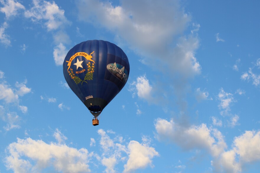 A hot air balloon is in the sky with a Nevada state flag design on the front of it.