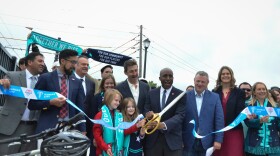 A group of people cut a ribbon and pose for a photo.