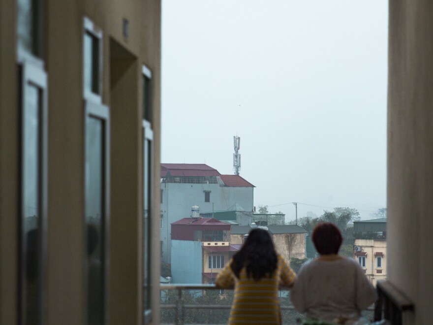 Residents of the quarantine center look out at the surrounding neighborhood.