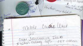 A photo of a notebook, paper, a cross, and sobriety chips.