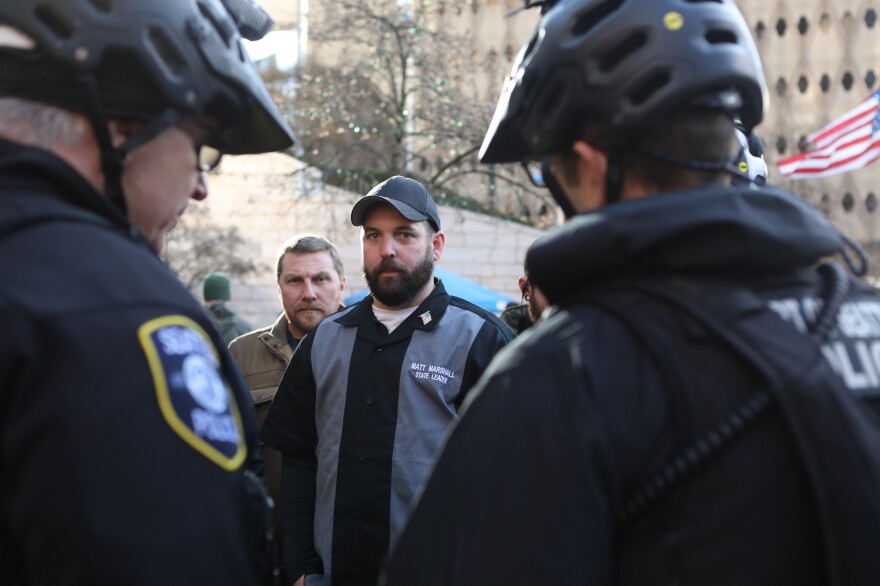 Matt Marshall, state leader of the Washington Three Percent, talks with law enforcement during the rally. He is trying to distance his group from the militia image.