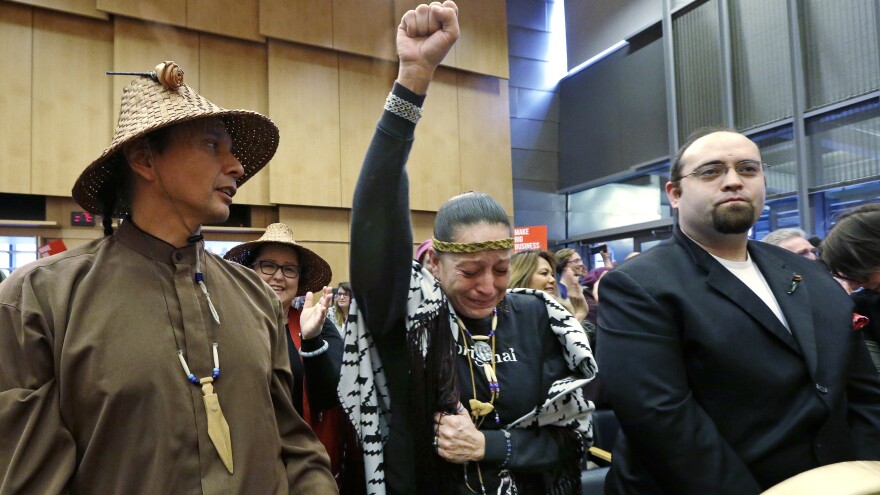 Olivia One Feather (center) of the Standing Rock Sioux tribe holds up her fist after the Seattle City Council voted Tuesday to divest from Wells Fargo over its role as a lender to the Dakota Access Pipeline project.