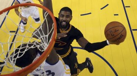 Cleveland Cavaliers guard Kyrie Irving, center, shoots against Golden State Warriors forward Draymond Green.