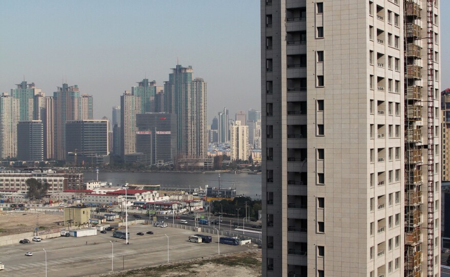 A luxury apartment tower rises near Shanghai's Huangpu River. Chen, an underground Christian who has sent his family to Los Angeles, hopes his home will be knocked down to make way for buildings like this one across the street, so Chen can use the compensation to buy a house in suburban LA.