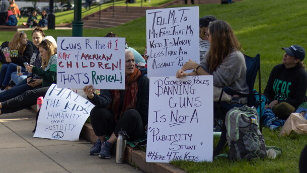 People sit in a sign holding home made signs.
