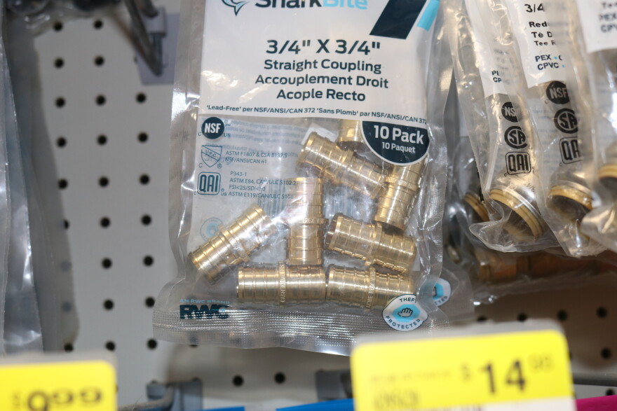 Plumbing parts that meet federal lead-free standards carry certification labels like 'Lead-Free per NSF/ANSI/CAN 372,' shown on these brass fittings at a Kotzebue store.