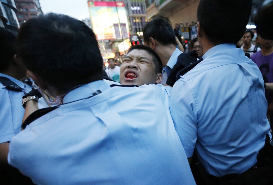 A student protester is injured after being pulled off and hit by residents and pro-Beijing supporters.