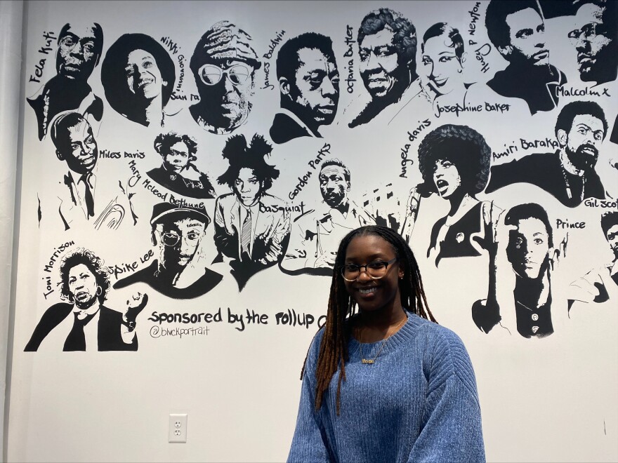 Brittani Taylor sat near portraits in Archive CLT that show influential Black figures on Dec. 21, 2022.