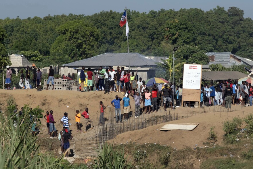 People stand near the construction of a canal.