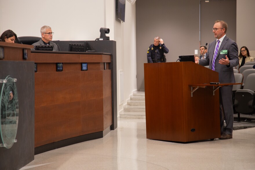 Image of a man at a public meeting, addressing city commissioners.