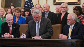 Gov. Eric Holcomb ceremonially signs SB4, the public health system overhaul bill, on Wednesday, May 24, 2023. Supporters of the law, including former Sen. Luke Kenley and State Health Commissioner Dr. Kristina Box (directly behind and to the right of Holcomb), look on.