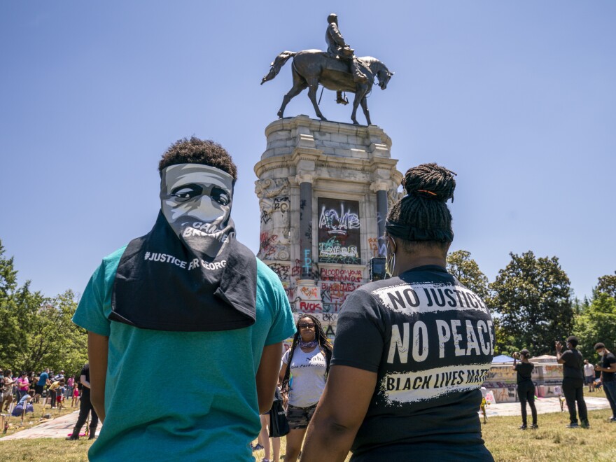 People gather at the Robert E. Lee Monument, now covered by protest graffiti, in Richmond, Va., on Sunday. A judge on Monday issued a temporary injunction against its removal.