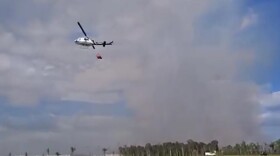 A firefighting helicopter that picks up a huge bucket of water and drops it on a wildfire works on the Newman Fire last week, east of Naples in Collier County
