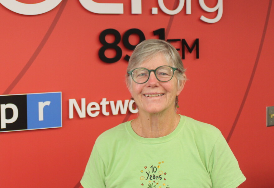 A woman in a green shirt and glasses smiles for a photo
