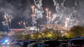 Fireworks explode over a lit-up stadium.