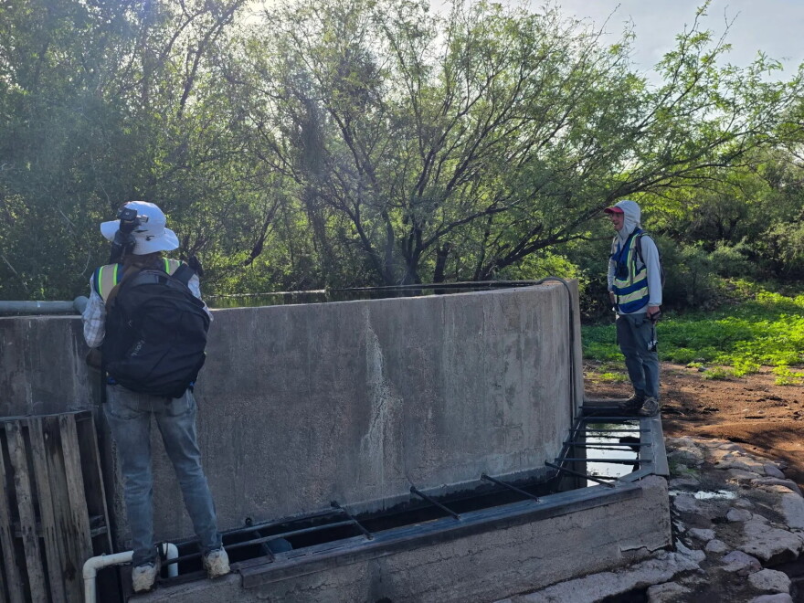 Volunteers Scott Larson and Pam Golden stand at a cattle tank on Friday, Aug. 14, 2026 south of Amado, Arizona.