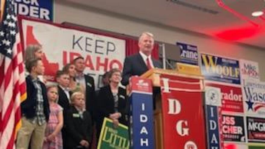 Gov. Brad Little standing at a podium in front of a small crowd of people.