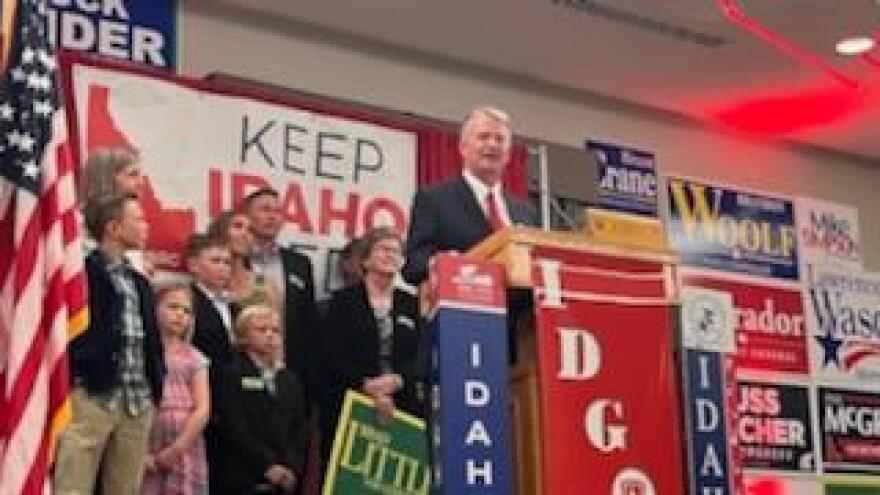 Gov. Brad Little standing at a podium in front of a small crowd of people. 