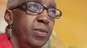 Headshot of a woman wearing glasses and a red blazer.