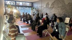 Participants sitting within AIMwell Yoga practicing arm yoga exercises 