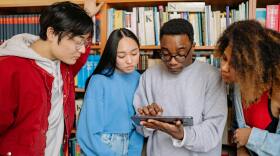 A group of students check their grades on an iPad.