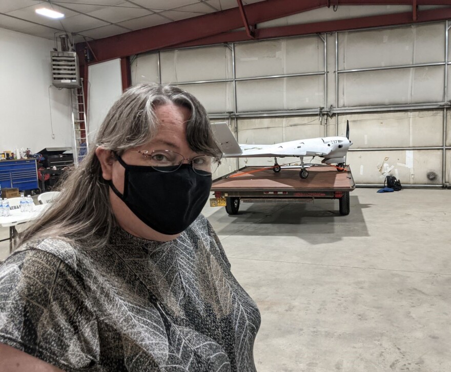 Cathy Cahill, director of UAF's Alaska Center for Unmanned Aircraft Systems Integration, in the ACUASI hangar at Fairbanks International Airport with a Sentry drone in the background.