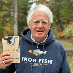 Author Michael Delp poses with a copy of his new book, "Of Blood and Rivers," a collection of elegies about grief and loss. (Photo: Ed Ronco/IPR News)
