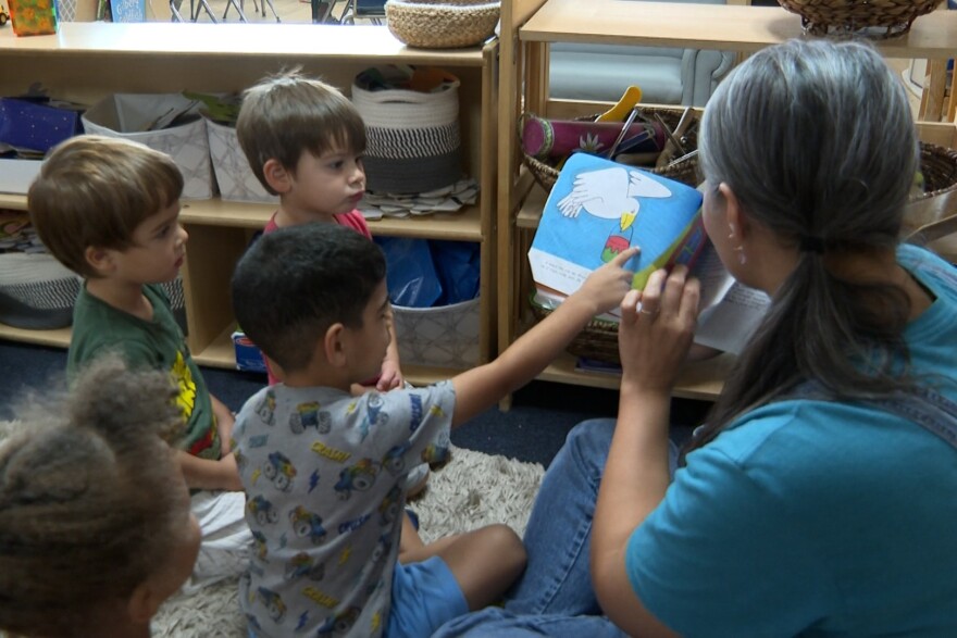 Michelle Paxton reads a book to a group of kids in the classroom.