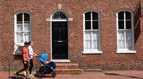A couple push their child in a stroller along a sidewalk in the Old Town section of Alexandria, Virginia. (Photo by Robert Alexander/Getty Images)