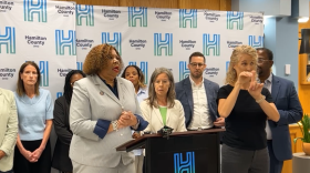 two women stand at a podium with people behind them