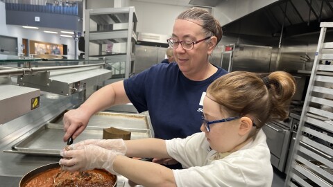 Sophia Nelson adds meat to tomato sauce for her lasagna, with the help of Angie Summers.