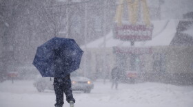 A man takes cover under an umbrella as snow comes down in the Fair Haven neighborhood of New Haven, Connecticut in Feb., 2021.