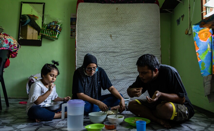 Mohd, right, eats with his wife, Tawhirah, center, and their daughter Hosna, left. Tawhirah is in her first trimester of pregnancy.