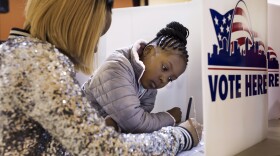 Jumira Moore, 8, watches as her mother, Timira Saunders, fills out a ballot at Central Baptist Church in St. Louis in November 2016.