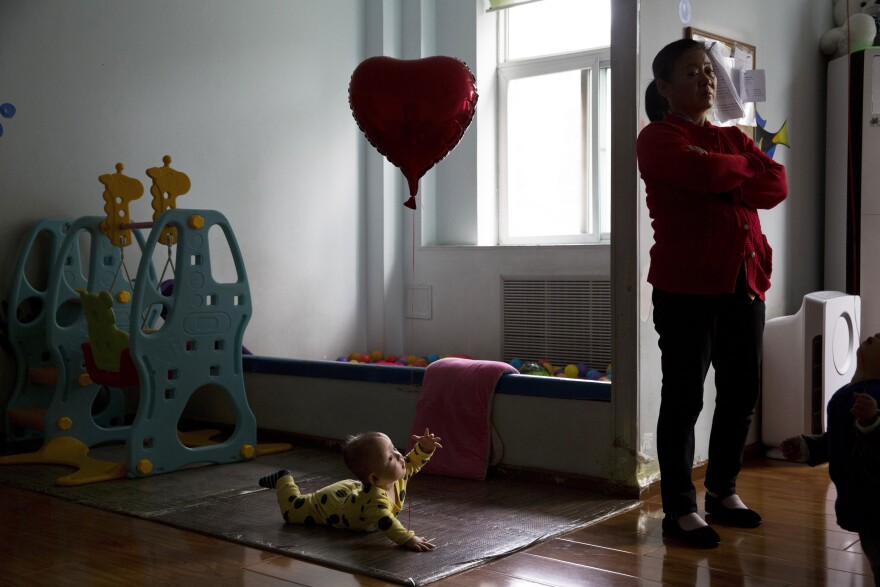 FILE - In this Wednesday, Oct. 11, 2017 file photo, a child reaches towards a minder at a foster home of the New Hope Foundation, a charity that provides care and medical treatment for babies with deformities that can be corrected with surgery, on the outskirts of Beijing, China. (AP Photo/Ng Han Guan)