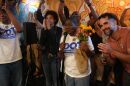 A woman surrounded by supporters holds flowers and a microphone
