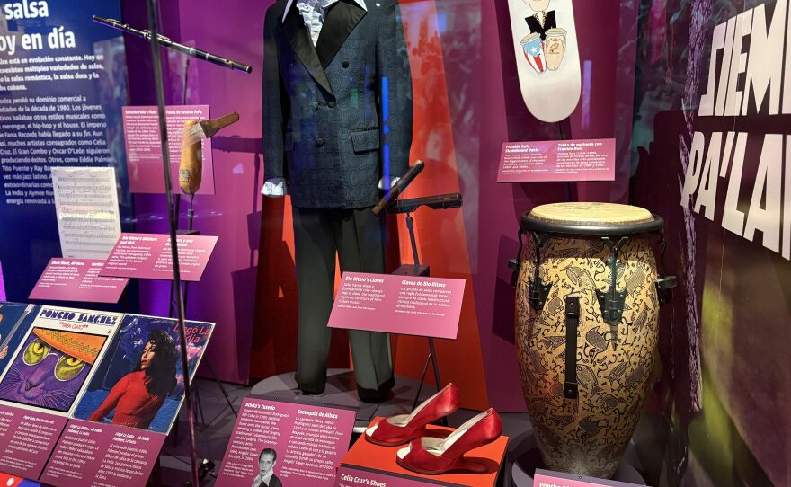 The exhibit features an antique flute from Miami salsa musicians Gerardo Peña and Albita, and a pair of red shoes that belonged to Celia Cruz.