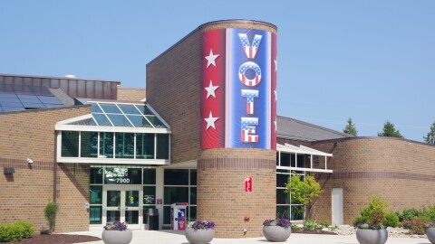 big banner on the Portage City Hall brown brick building that says "vote" in vertical letters with a red-white-and-blue theme