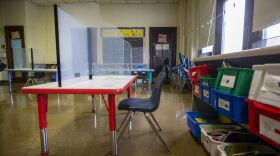 A look inside an empty classroom with plexiglass on a desk.