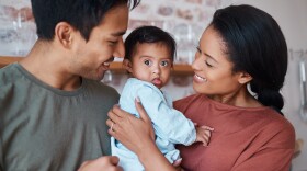 Two parents holding a baby between them