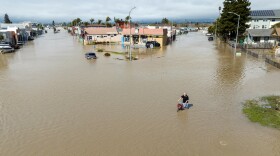 An aerial view shows a man navigating floodwaters with his bicycle in the unincorporated community of Pajaro in California on March 11. Residents were forced to evacuate in the middle of the night after an atmospheric river surge broke the Pajaro Levee and sent flood waters flowing into the community.