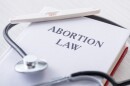 selective focus of pregnancy test on book with abortion law lettering near stethoscope