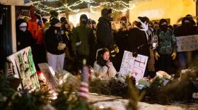 A woman kneels and prays as hundreds gather around a growing memorial site at 26th Street West and Nicollet Avenue, where federal agents shot and killed a 37-year-old Alex Pretti Saturday, Jan. 24, 2026, earlier in the day.