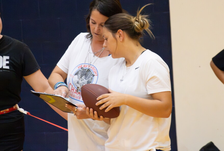 Wichita Northwest High School sophomore Avery Soetaert consults with her coach Brooke Collins during flag football practice at the school.