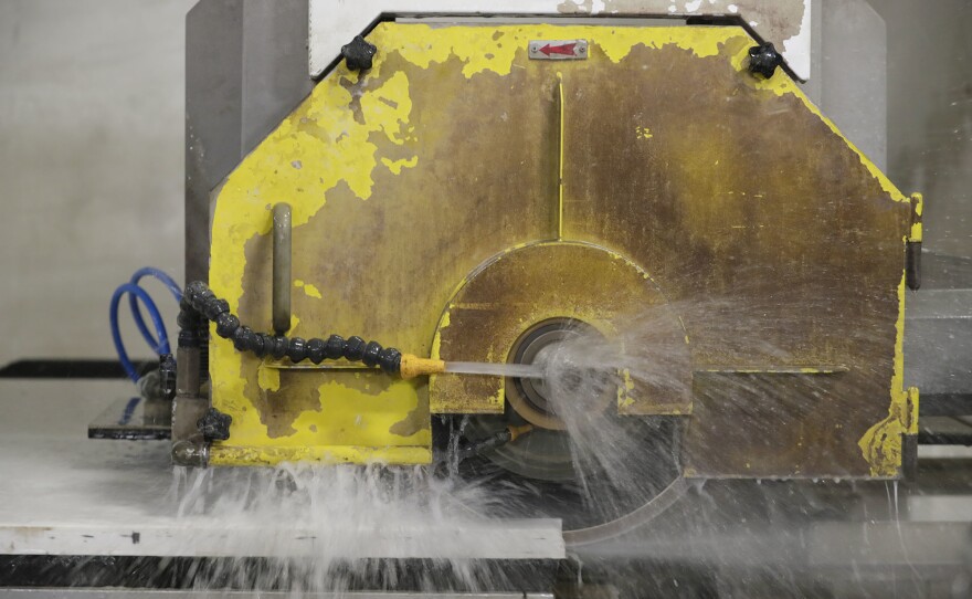 Water applied to cutting equipment, like this computer-operated saw, is one method to control silica dust exposure when cutting quartz slabs.