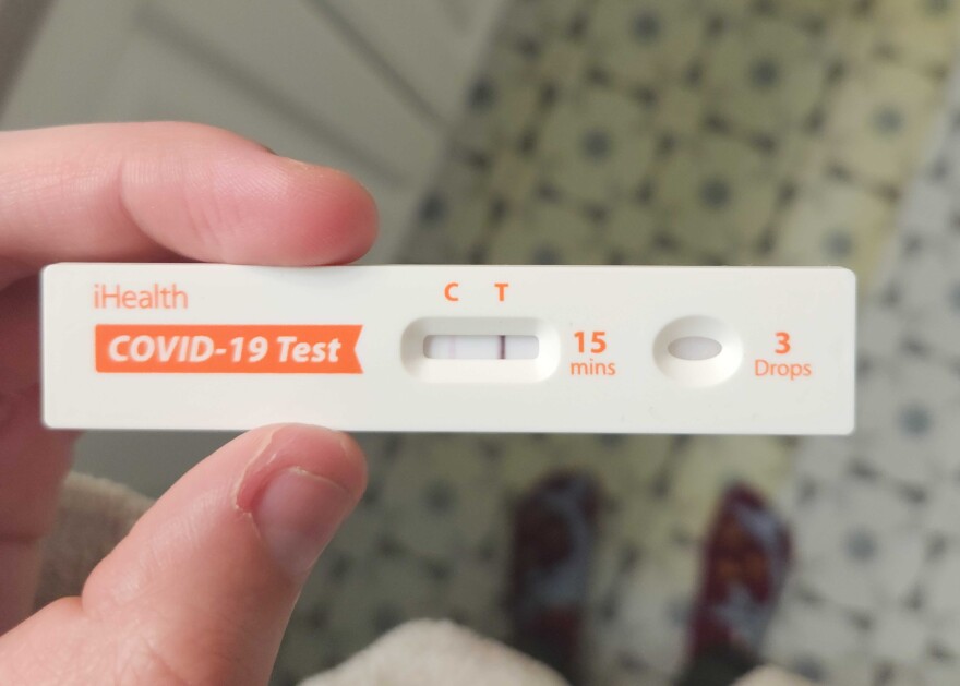 A hand holds a COVID-19 test that shows a strong positive result. 