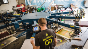 An Ink Floyd employee prints a design on the printing press.