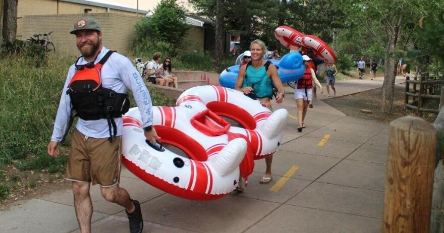 Mulitple people carry inner tubes on a sidewalk.